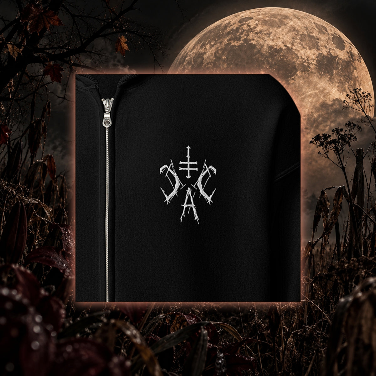 Detailaufnahme eines schwarzen Zip-Hoodies von Cultural Carnage Apparel mit weißem gesticktem CCA-Logo auf der Brust und silbernem Reißverschluss.